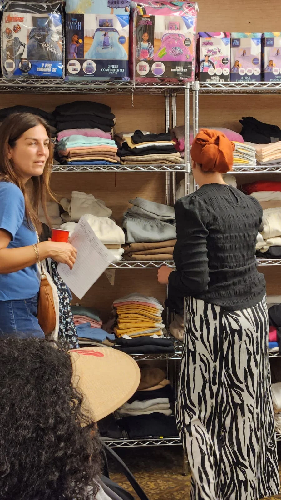 People browsing donated clothing on shelves and rails